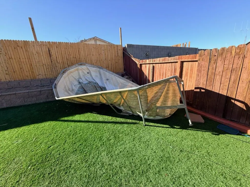 Old collapsed above-ground pool sitting on artificial turf in a Downtown Henderson back yard before residential junk removal