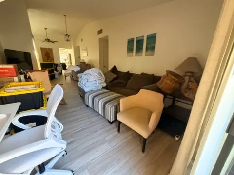 Green Valley North living room filled with older furniture, exercise equipment, and items ready for removal